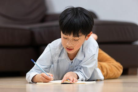少儿做作业小男孩趴在地上做作业背景