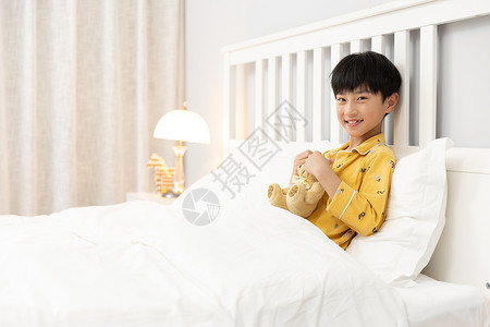 抱玩具熊的男孩小男孩抱着玩偶熊躺在床上背景