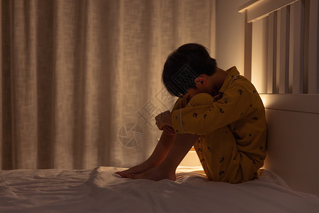 伤心哭泣男孩坐在床上哭泣的小男孩背景