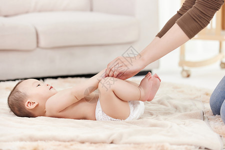 母亲给婴儿宝宝伸展四肢按摩图片
