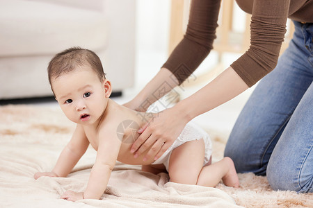 女性的手仔细给婴儿擦拭身体乳高清图片