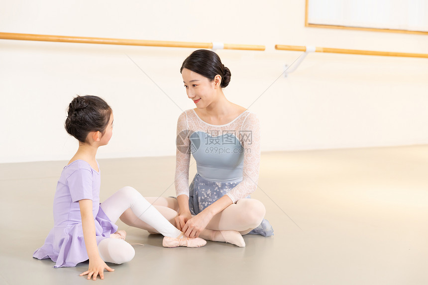 芭蕾舞老师帮助小女孩系鞋带图片