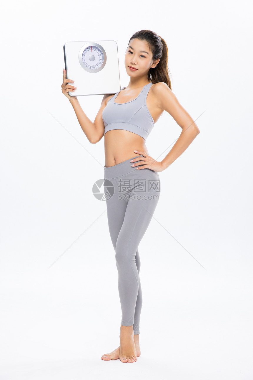手拿体重秤的健身女性图片