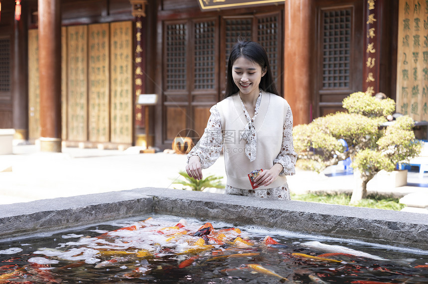 美女大学生逛寺庙喂食金鱼图片