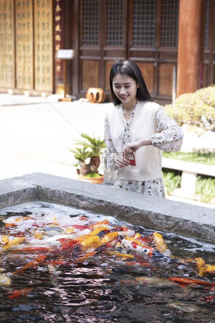 美女大学生逛寺庙喂食金鱼图片