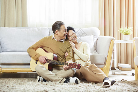 坐着弹吉他快乐的中老年夫妇在客厅弹吉他背景