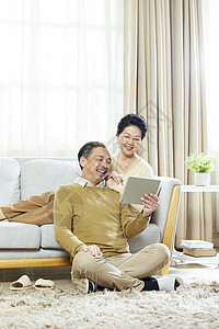快乐的老年夫妇在客厅使用平板电脑高清图片