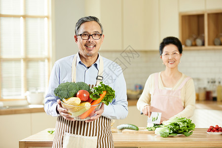 带围裙的中老年男士手捧新鲜蔬菜图片