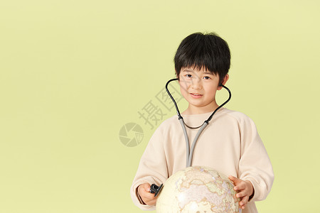 小男孩把听诊器放在地球模型上背景图片