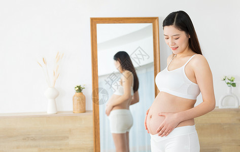 低头抚摸肚子的孕妇背景图片
