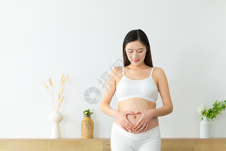 在肚子前面做爱心手势的孕妇图片