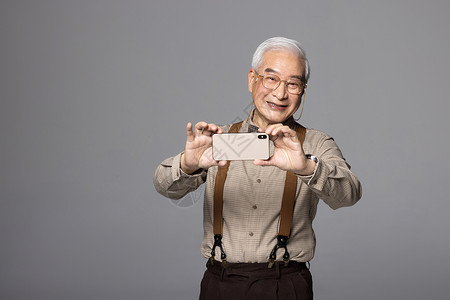 使用智能手机拍照的老人图片