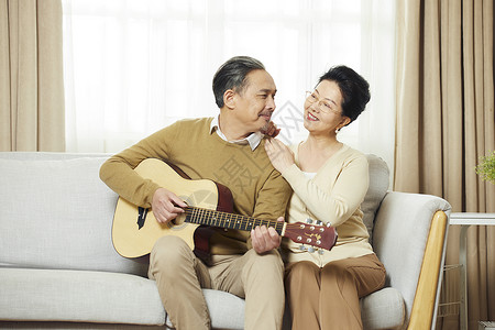 快乐的中老年夫妇在客厅弹吉他对视图片
