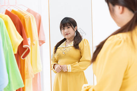 胖子穿衣搭配技巧肥胖女性对着镜子展示自己身材背景