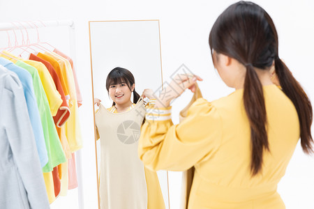 肥胖女性对着镜子挑选服装高清图片