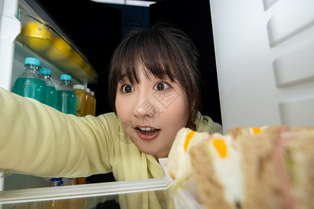 饥饿的脸女性晚上打开冰箱找食物背景