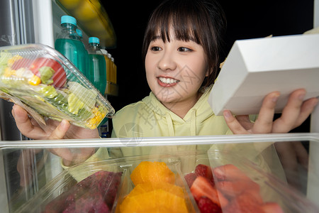 女性晚上打开冰箱拿取食物高清图片