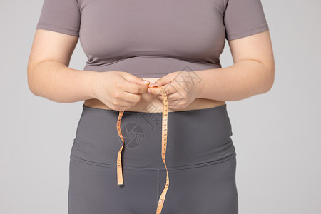 女性用皮尺测量腰围特写图片