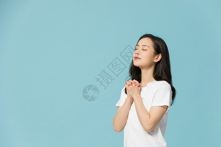 年轻女性闭眼祈祷许愿背景图片