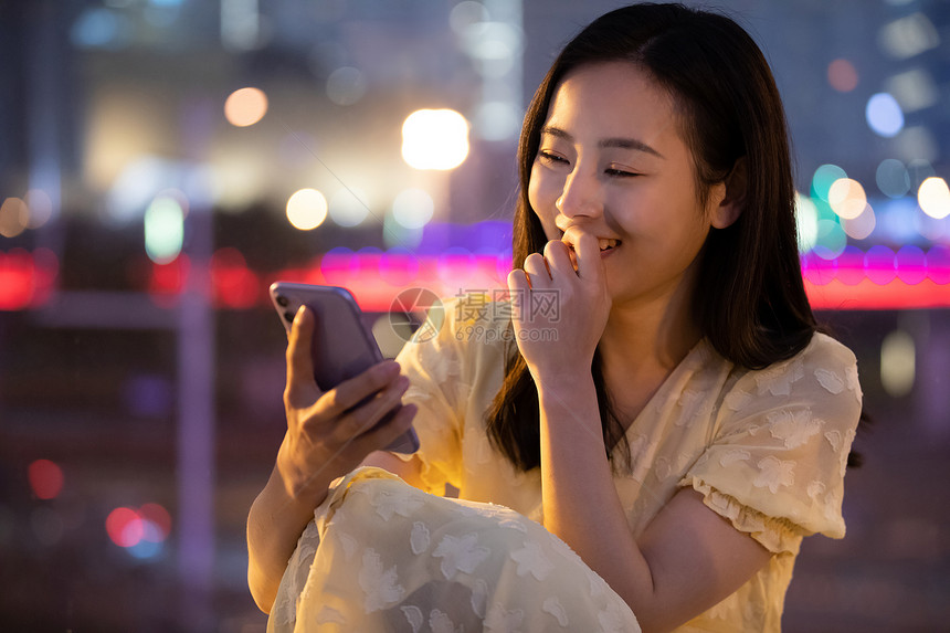 拿着手机笑的很开心的女性图片