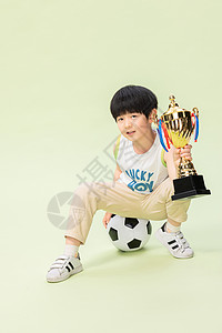 小男孩踢足球得奖杯背景图片
