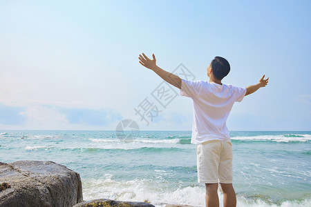 男青年张开手臂面朝大海背影背景