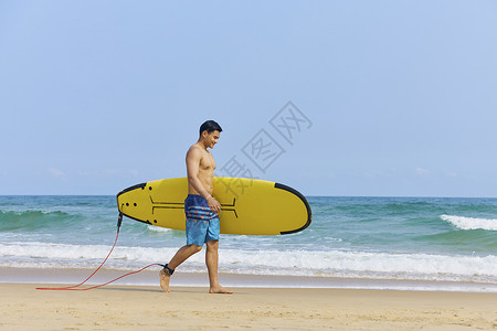 夏日冲浪男青年手拿冲浪板海边行走背景