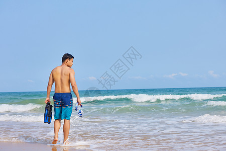 潜水脚蹼青年男性手拿潜水装备背影背景