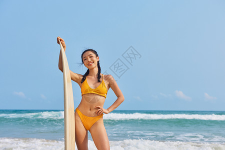 沙滩裤海边比基尼美女手拿冲浪板背景