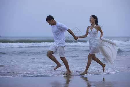 海边奔跑的人傍晚年轻情侣海边牵手奔跑背景