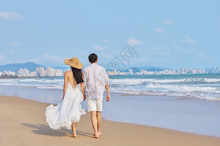 夏季海边美女年轻情侣牵手海边散步背影背景
