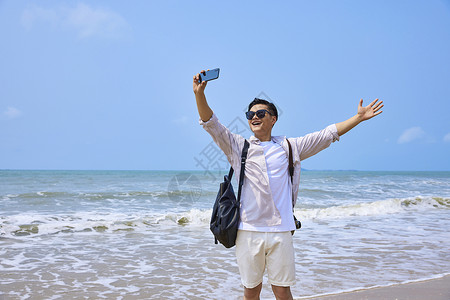 手臂举着手机年轻男士海边旅行自拍背景