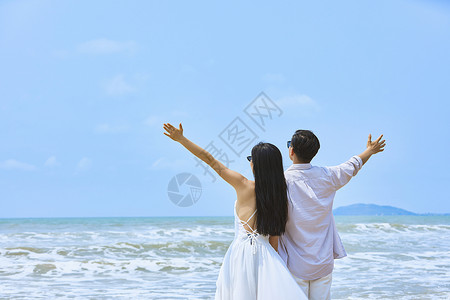 唯美白色海滩年轻情侣张开手臂拥抱大海背景
