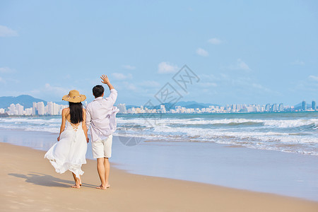 年轻情侣牵手海边散步背影图片