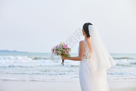 海洋造型素材海边穿婚纱的美女手拿手捧花背影背景