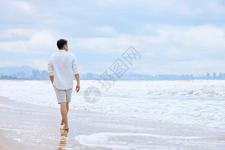 年轻男士夏天海边散步背影背景图片