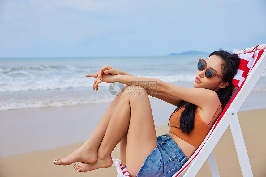 年轻美女海边度假沙滩椅休息图片