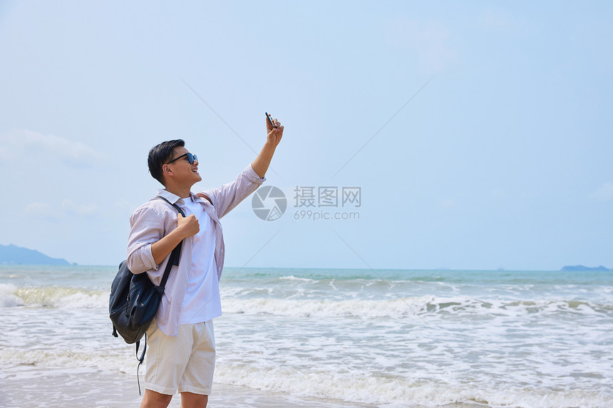 年轻男士海边旅游拍照图片