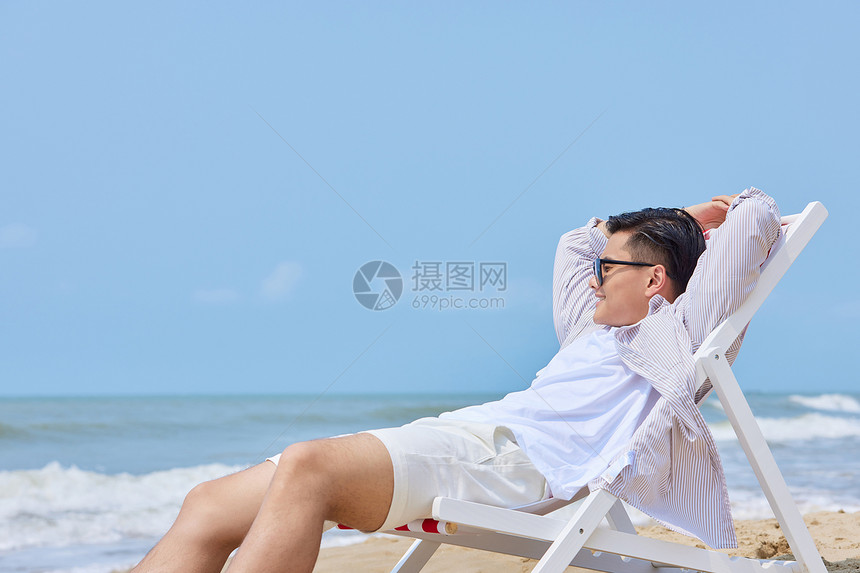 年轻男生海边度假沙滩椅上休息图片