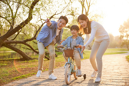 家长与小孩父母教儿子骑自行车背景