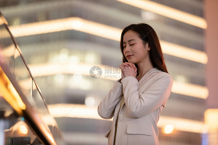 夜晚在城市祈祷的年轻女性图片