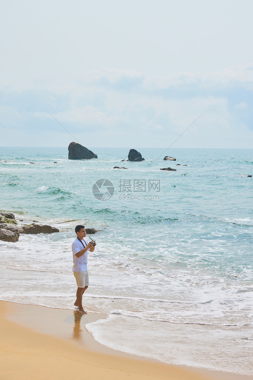 年轻男士拿着相机海边旅行拍照图片