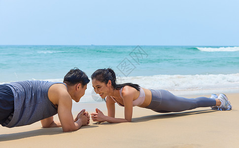 年轻情侣海边做平板支撑背景图片