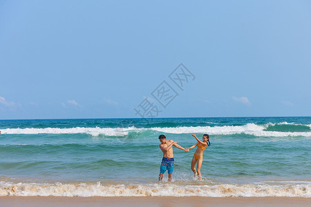 三亚比基尼年轻情侣海边戏水打闹背景