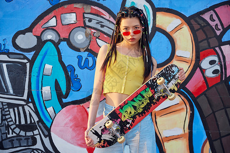 个性模特时尚美女涂鸦墙边玩滑板背景