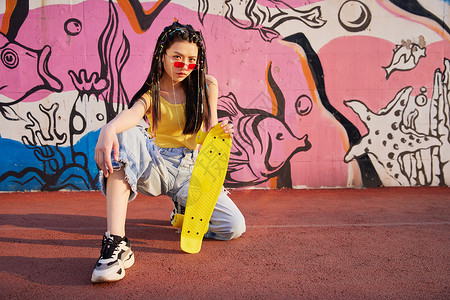 时尚美女涂鸦墙边玩滑板背景图片