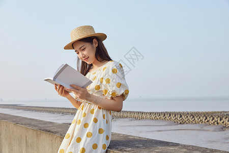 假期海边游玩在看书的悠闲女性背景