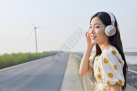 带耳机素材在马路边带耳机听歌的悠闲少女背景