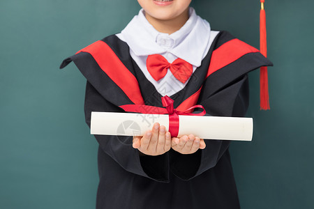 穿着学士服的小男孩递出毕业证书特写图片