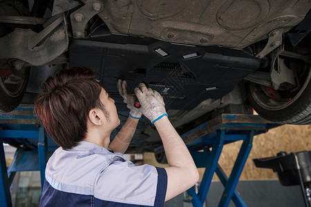 男性汽车修理工检查汽车底盘背景